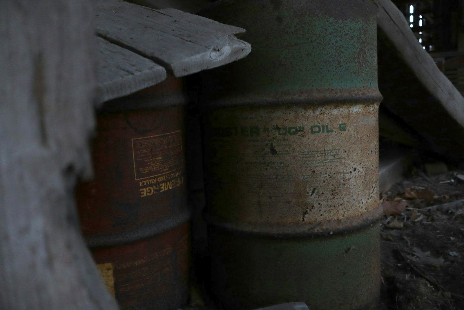 Vecchi fusti metallici arrugginiti impilati in un locale buio
